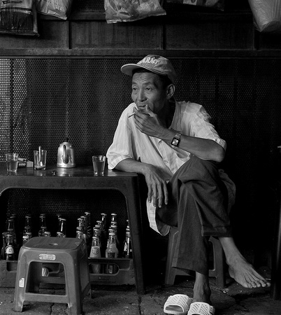 Pedicab driver having some tea and a smoke, Saigon