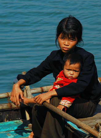 Young woman and child begging from a skiff on Ha Long Bay, Vietnam